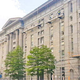 Construction workers using PowerMast scaffolding systems on a building facade.