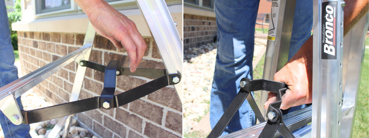 Close-up of hands securing the steel spreader mechanism on a Bronco three-legged scaffold. The ladder is set up outdoors on grass and near a brick wall.